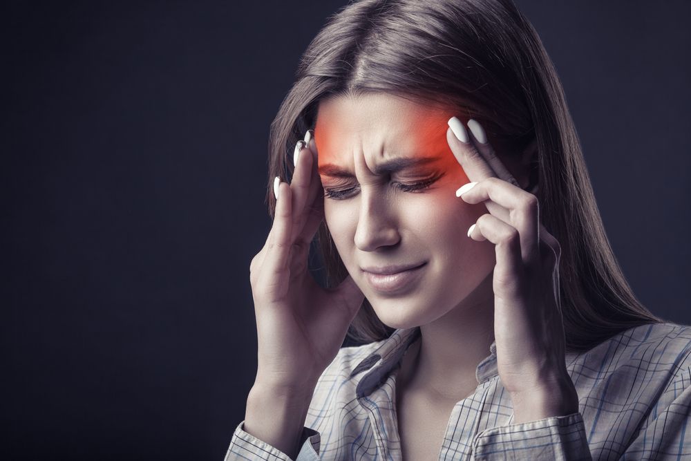 A woman is holding her head in pain because of a headache.