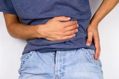 A man is holding his stomach in pain.