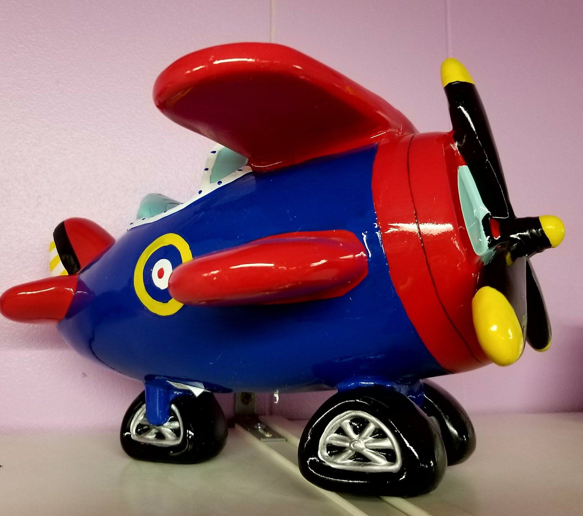 A blue and red toy airplane with a yellow propeller