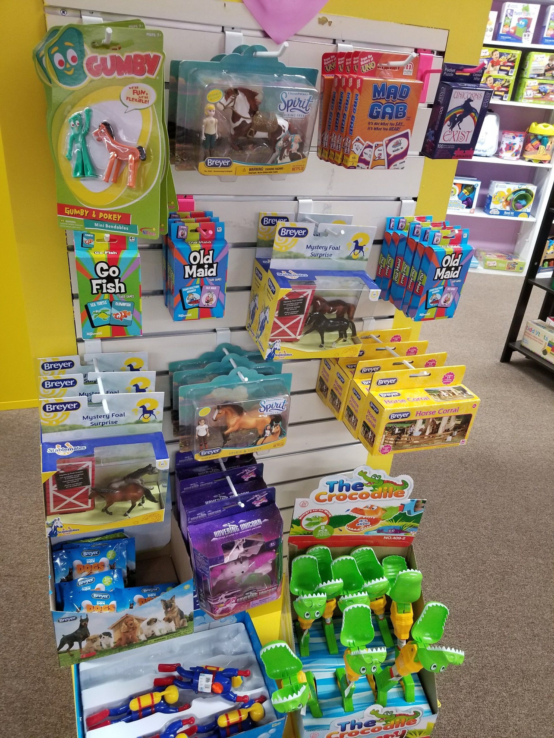 A bunch of toys are hanging on a wall in a store.