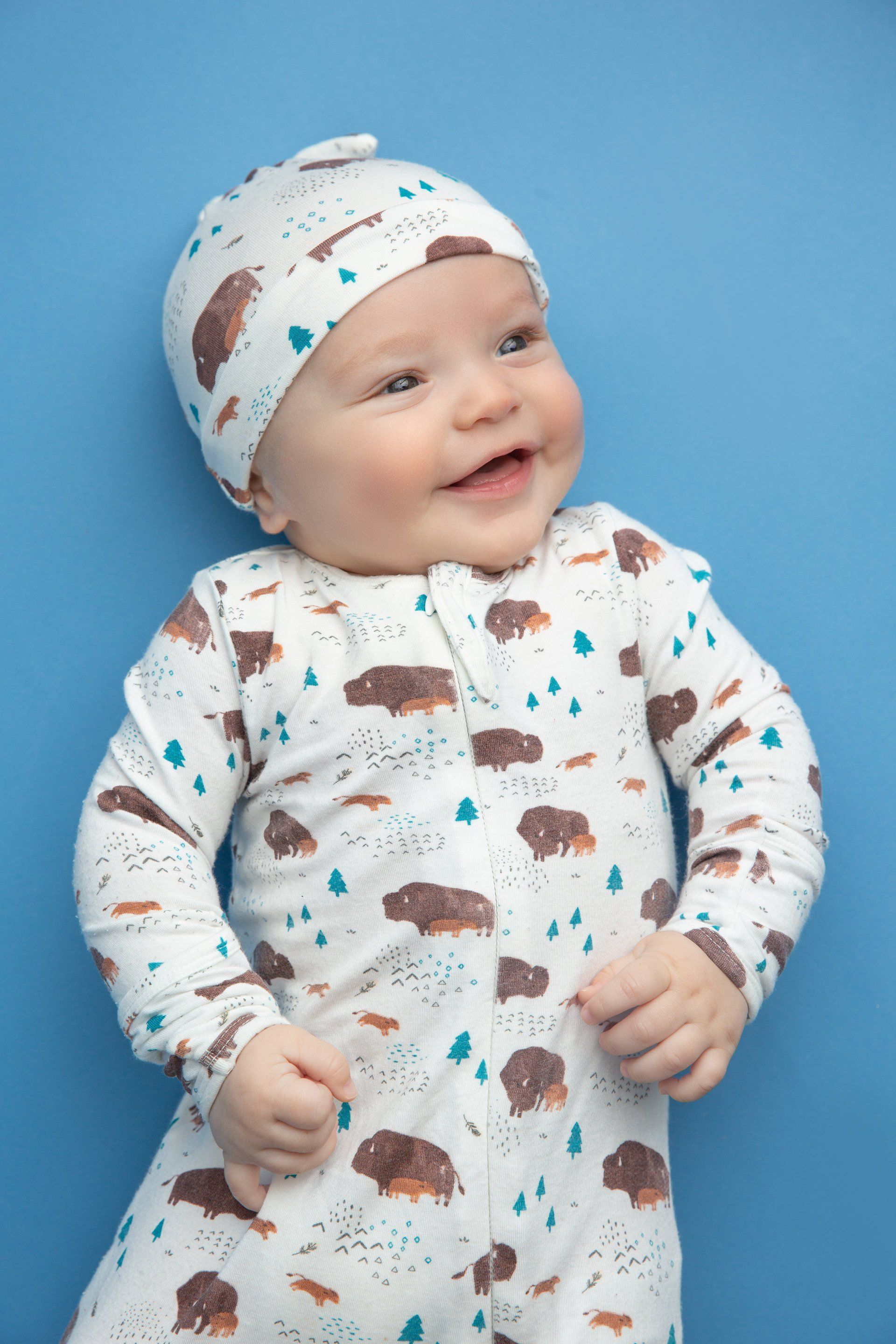 A baby is wearing a white onesie and a hat.