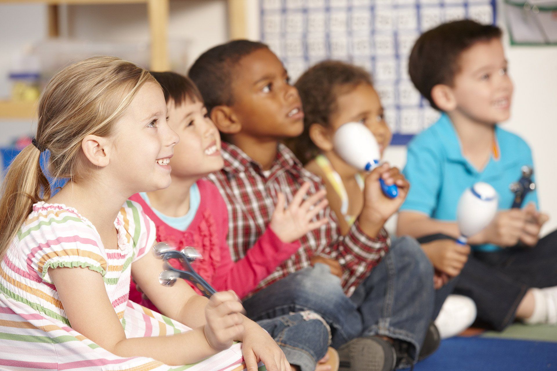 A group of children are sitting on the floor holding maracas.