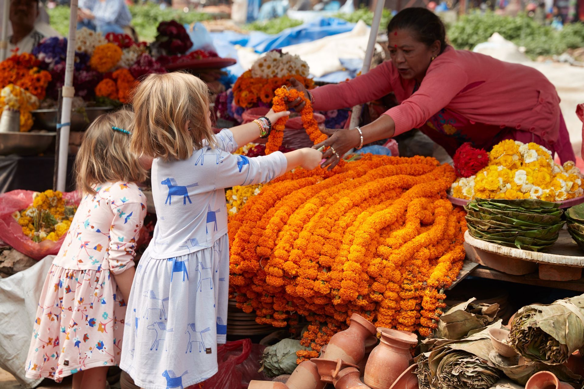 Two little girls are looking at flowers at a market.