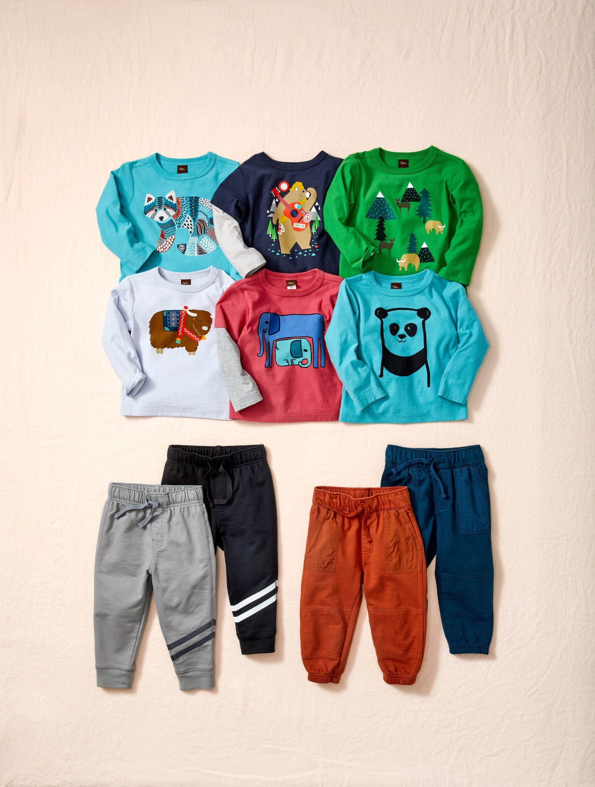 A bunch of baby clothes are lined up on a table.