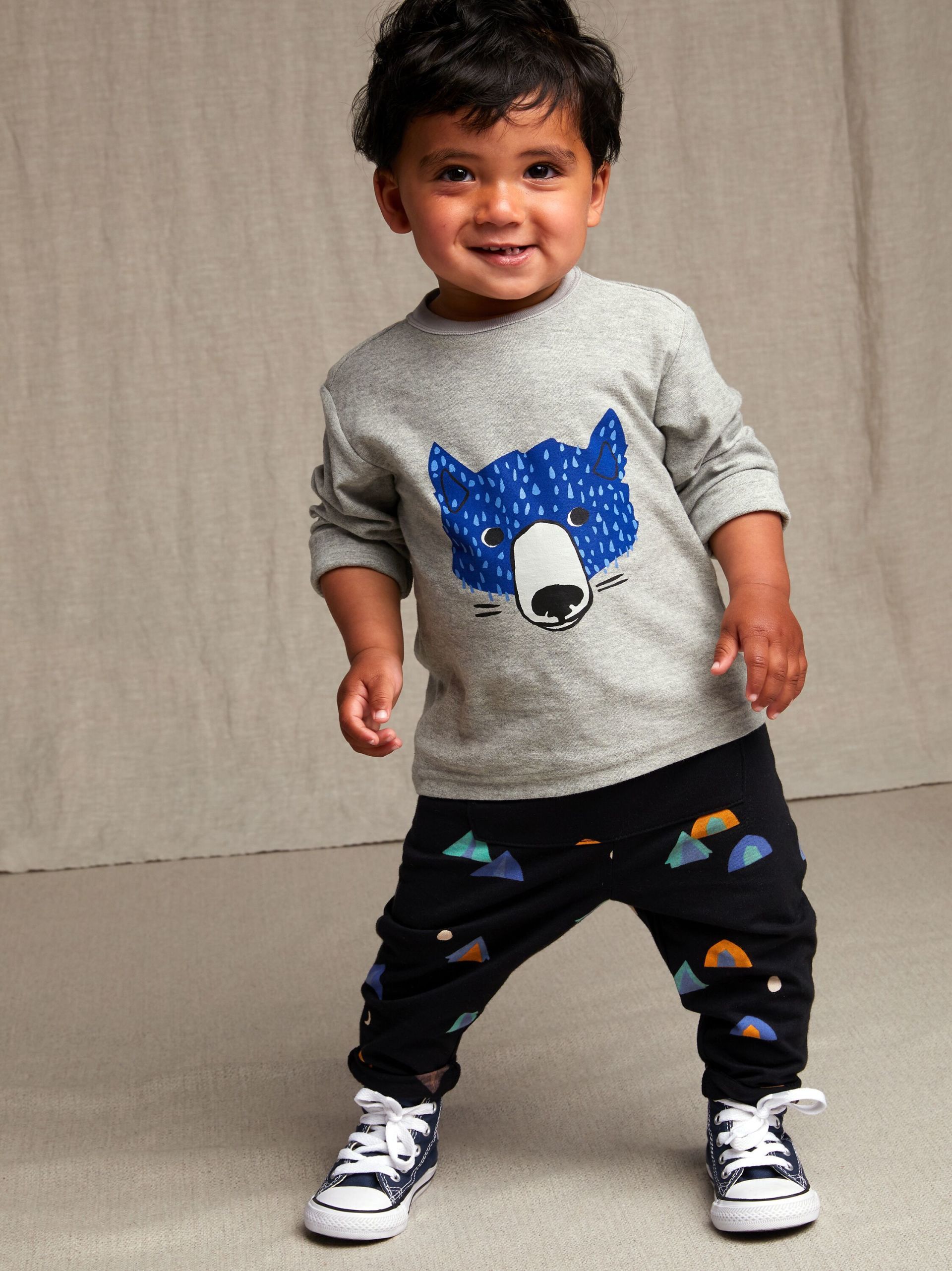 A little boy wearing a gray shirt with a blue bear on it