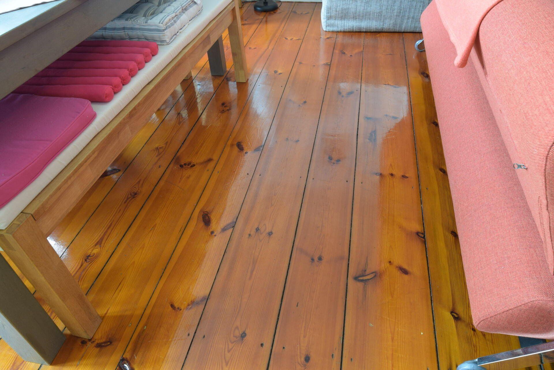 Ein Holzboden mit einer Bank und einer Couch im Hintergrund