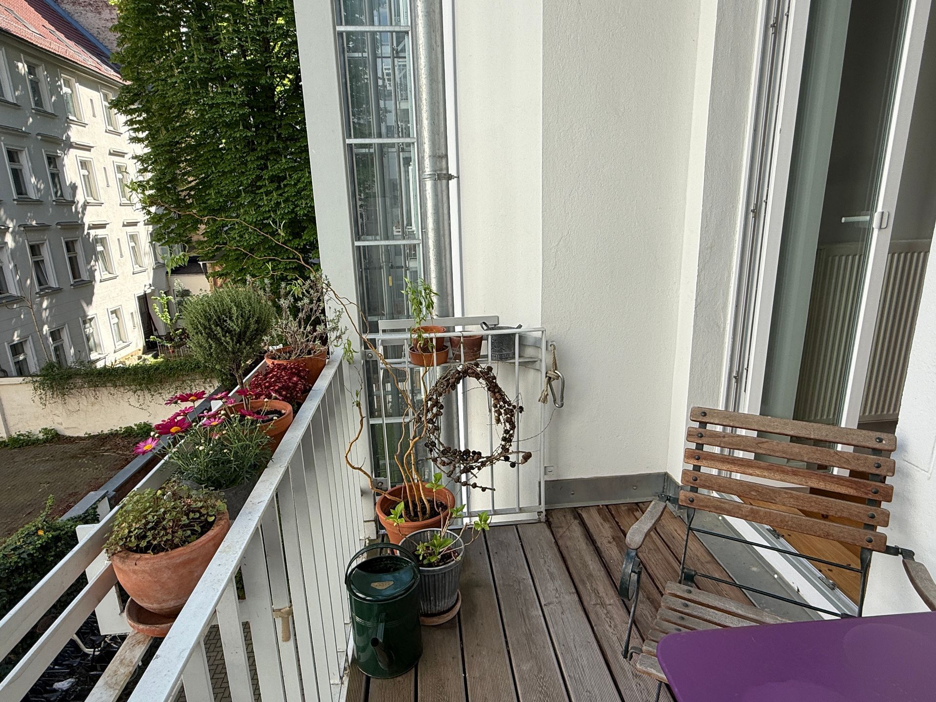 Ein Balkon mit Topfpflanzen und einem lila Tisch