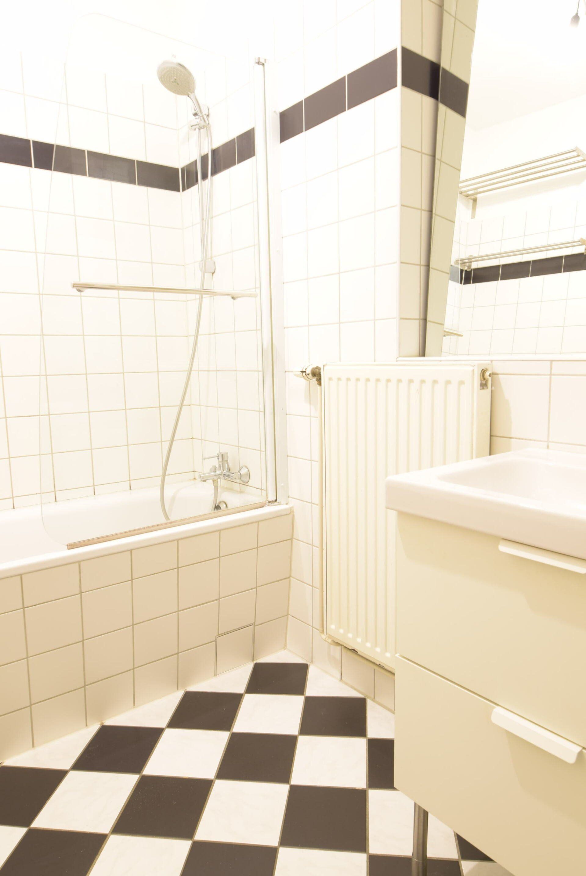 Ein Badezimmer mit schwarz-weiß kariertem Boden und einer Badewanne.