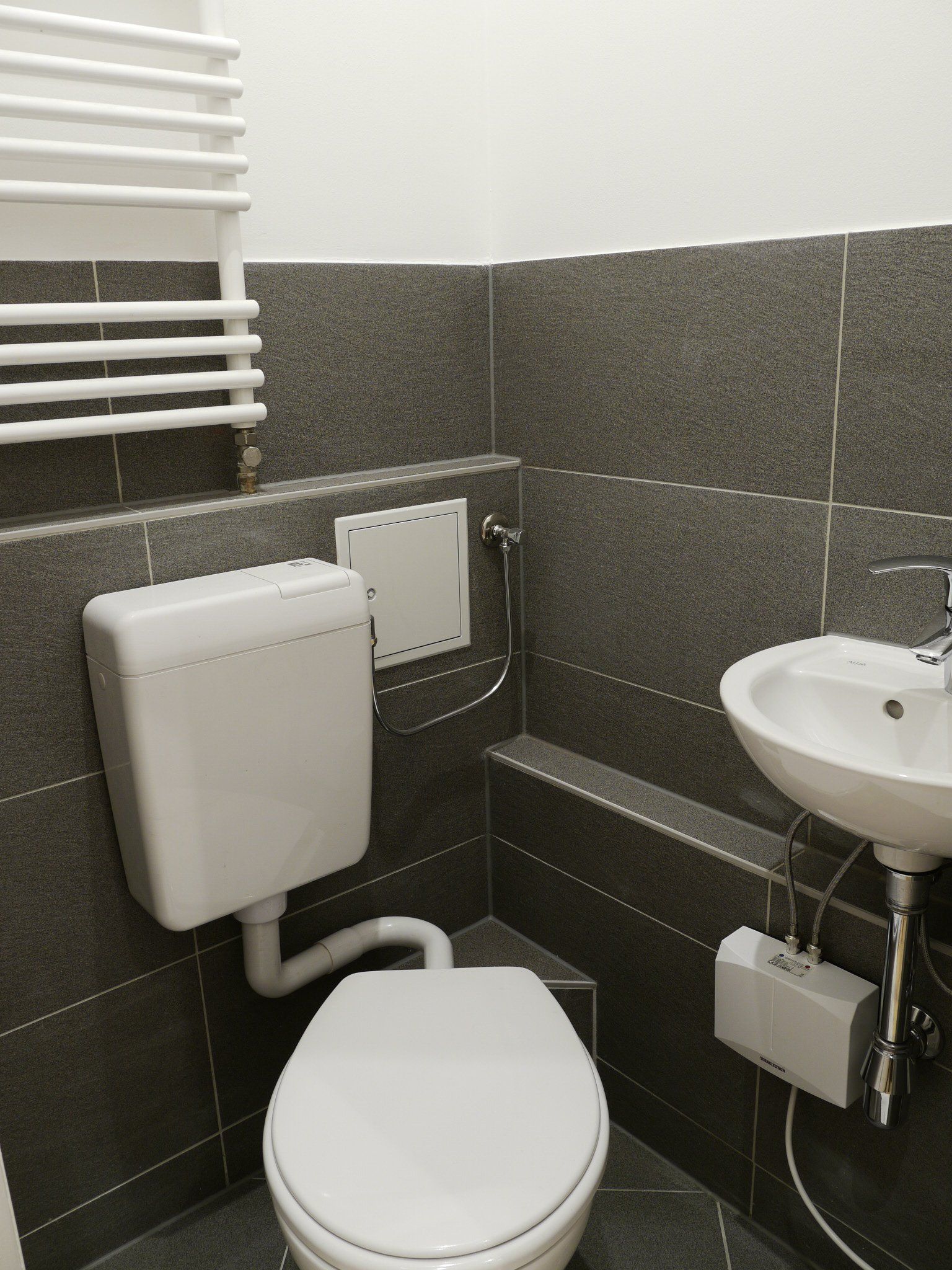 Ein Badezimmer mit Toilette, Waschbecken und Handtuchhalter