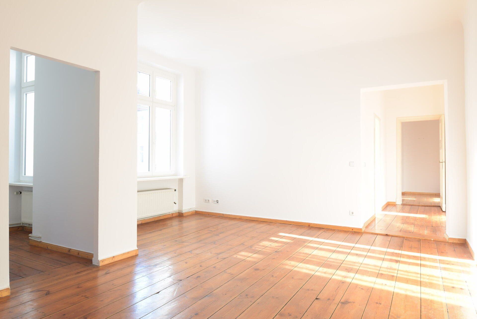 Ein leeres Wohnzimmer mit Hartholzböden und weißen Wänden.