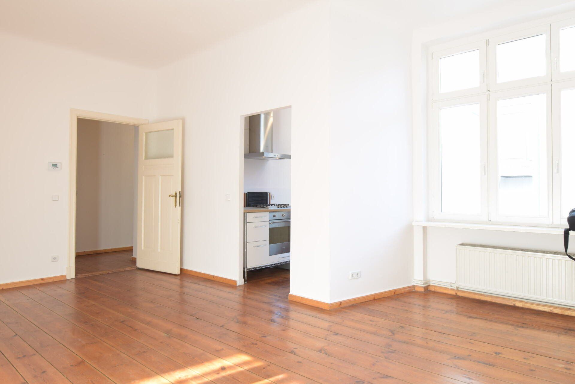 Ein leeres Wohnzimmer mit Hartholzböden und weißen Wänden.