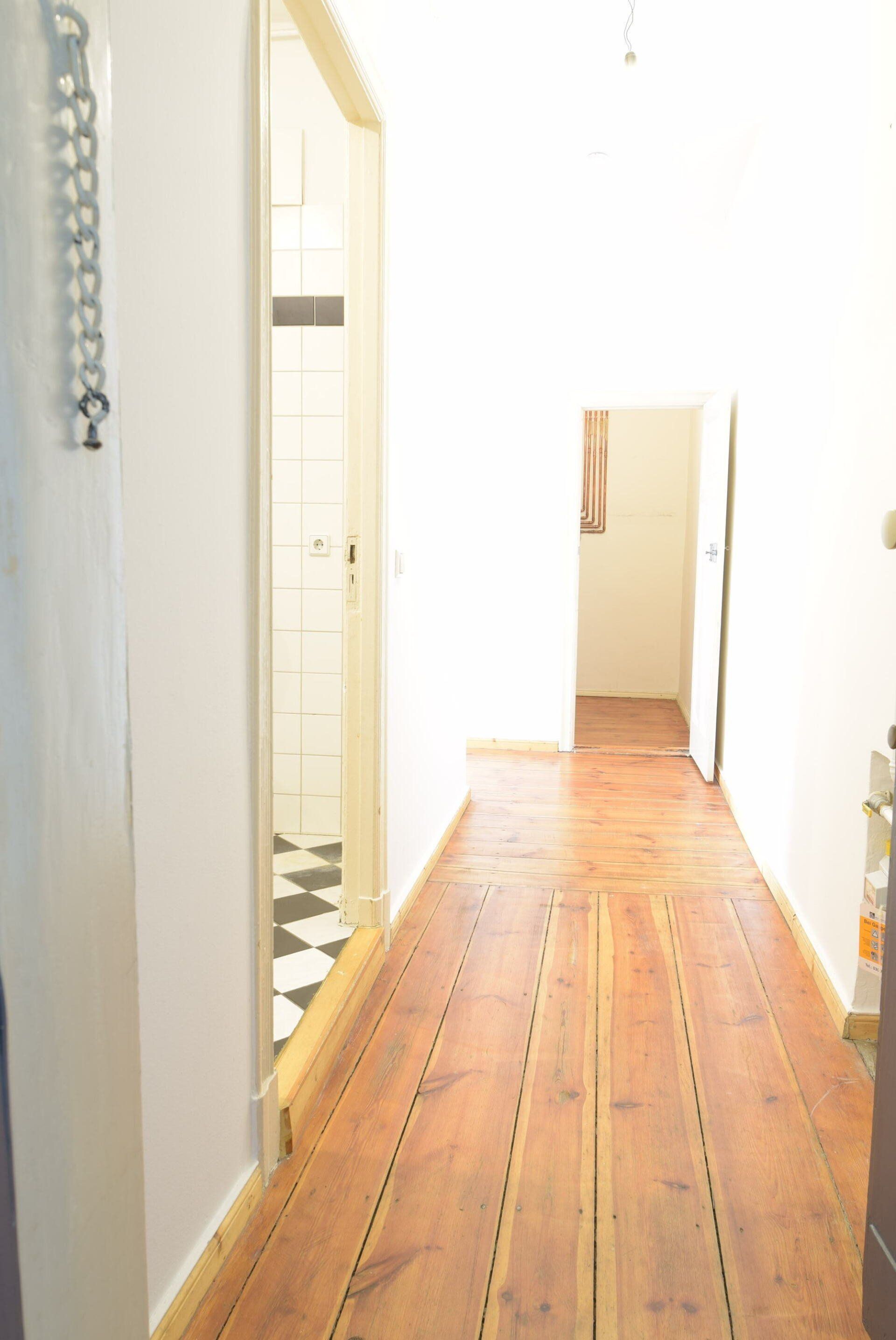 Ein Flur mit Holzboden und weißen Wänden