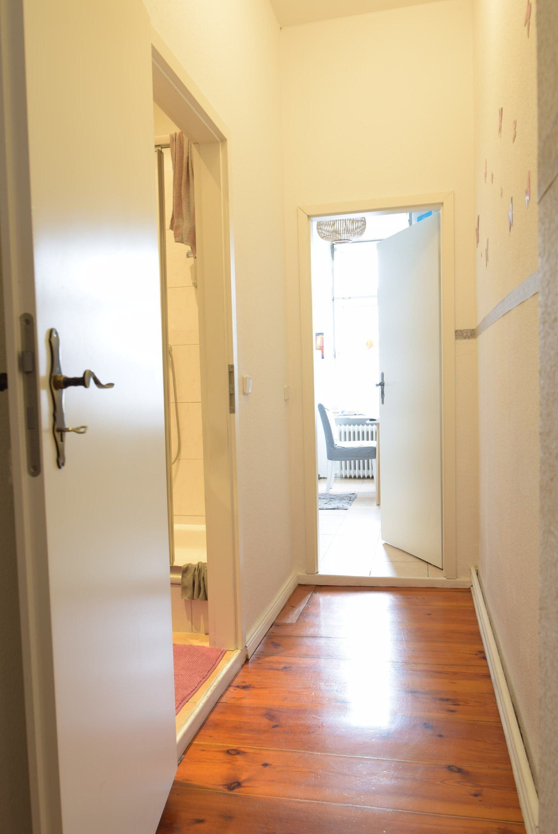 Ein Flur mit Holzboden und einer weißen Tür