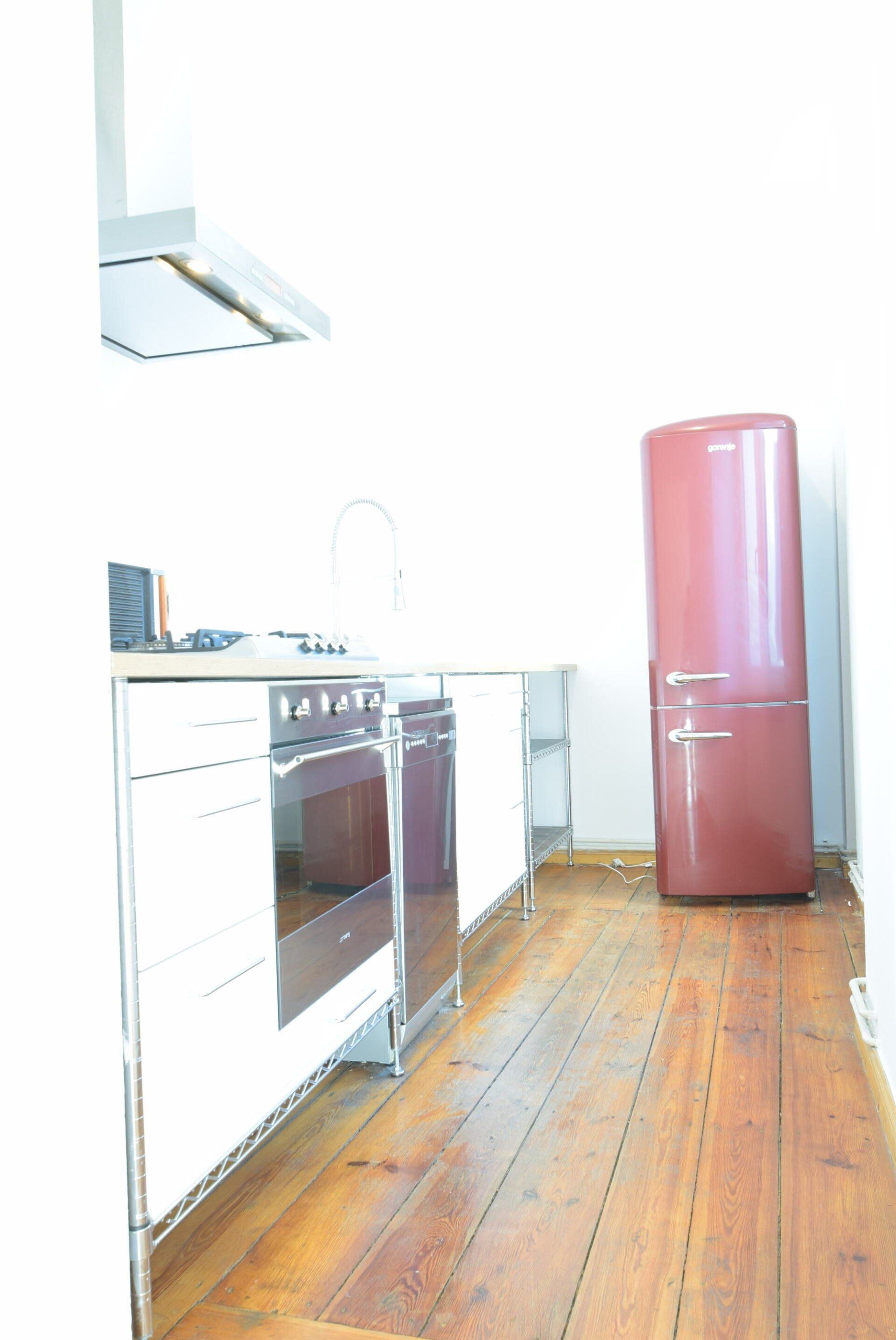 Eine Küche mit einem roten Kühlschrank und weißen Schränken