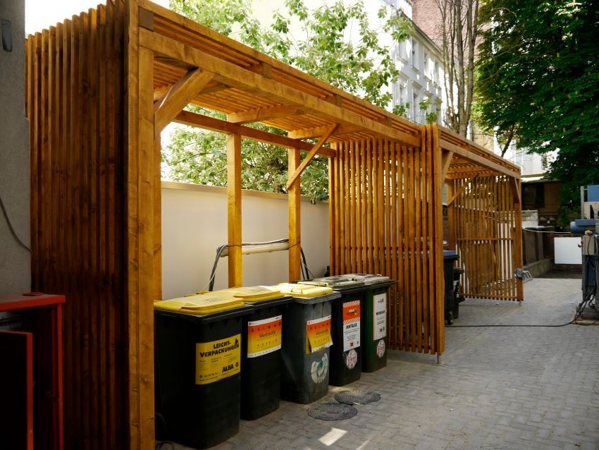 Eine Holzkonstruktion mit Mülltonnen darunter