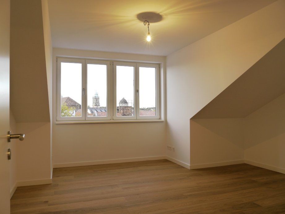 Ein leerer Raum mit schräger Decke und einem Fenster