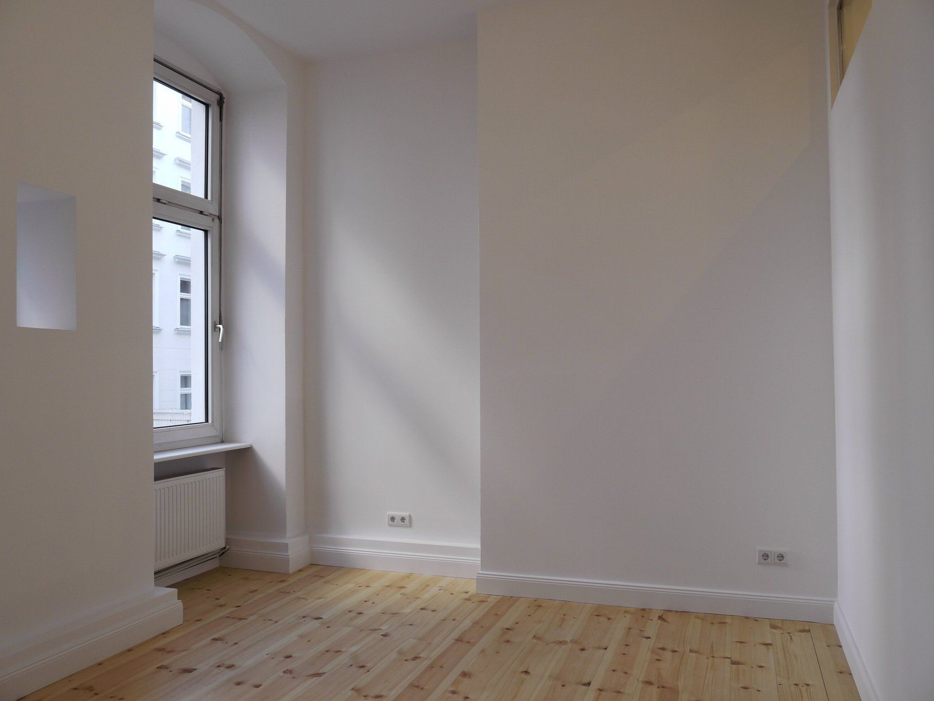 Ein leerer Raum mit Holzboden und weißen Wänden