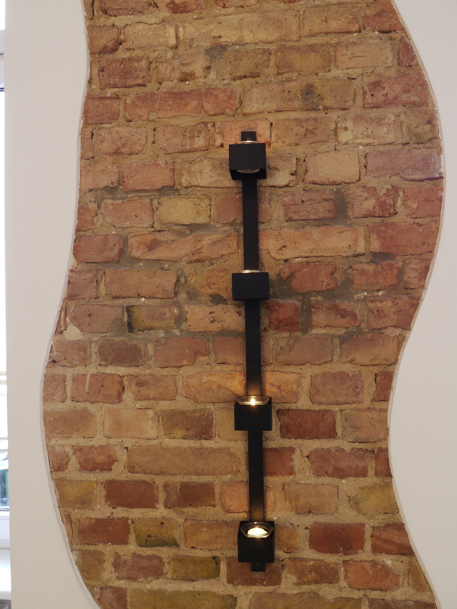 Eine Ziegelwand mit einem Kerzenhalter darauf