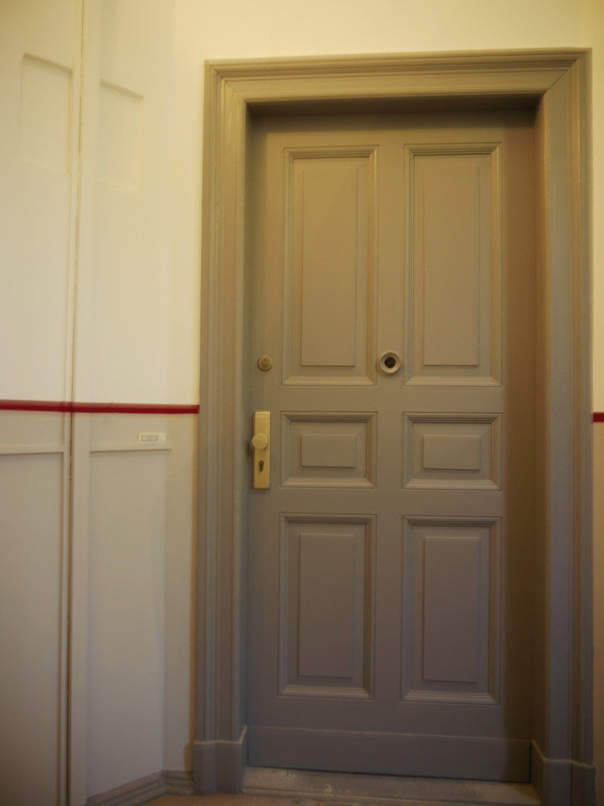 Eine graue Tür mit einem goldenen Griff in einem Flur