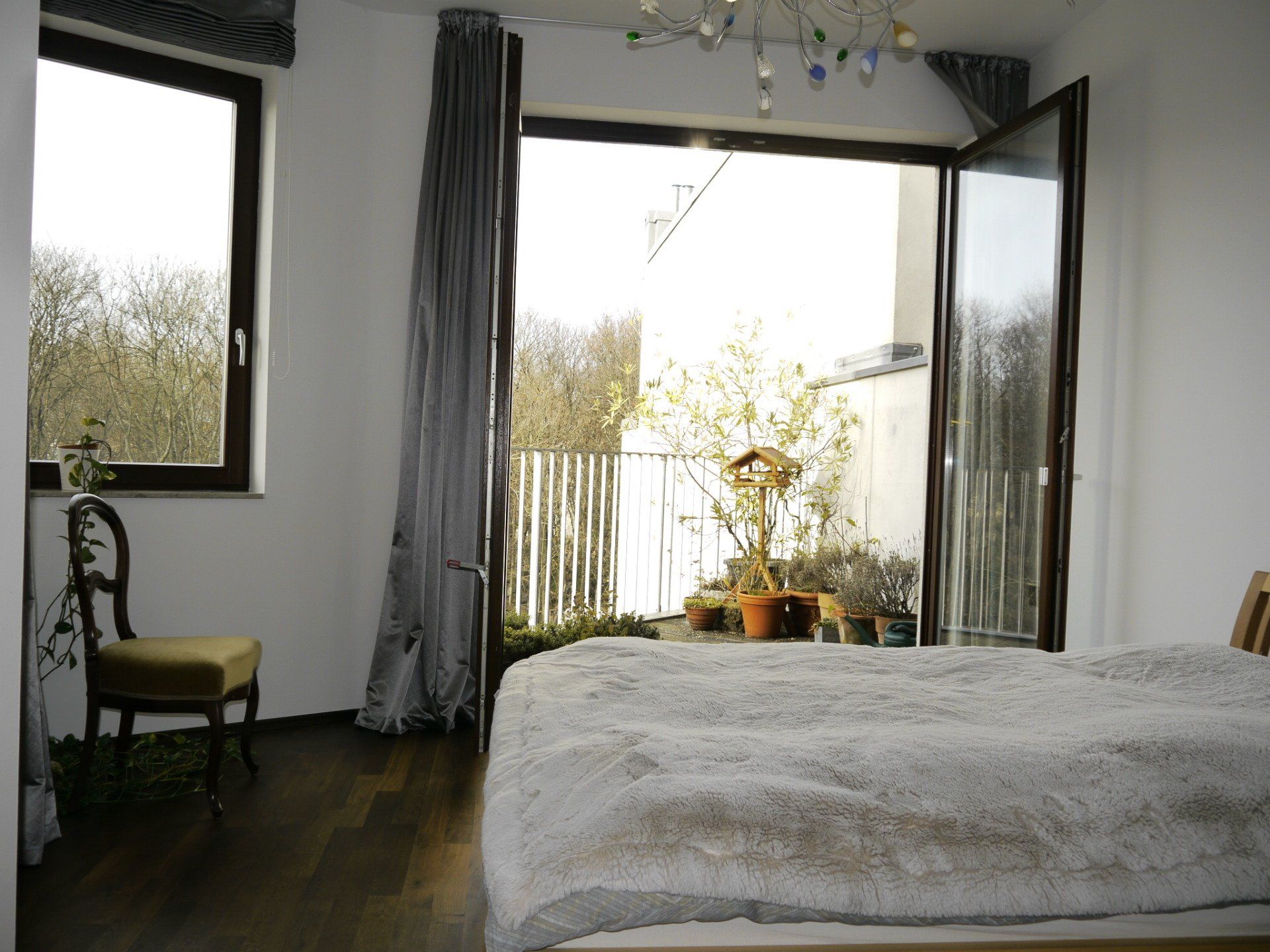 Ein Schlafzimmer mit Bett, Stuhl, Fenster und Balkon.