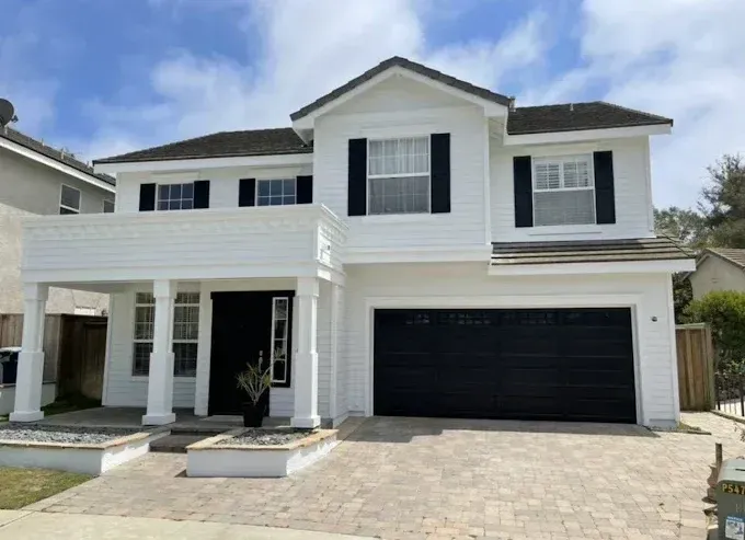 A white house with black shutters and a black garage door