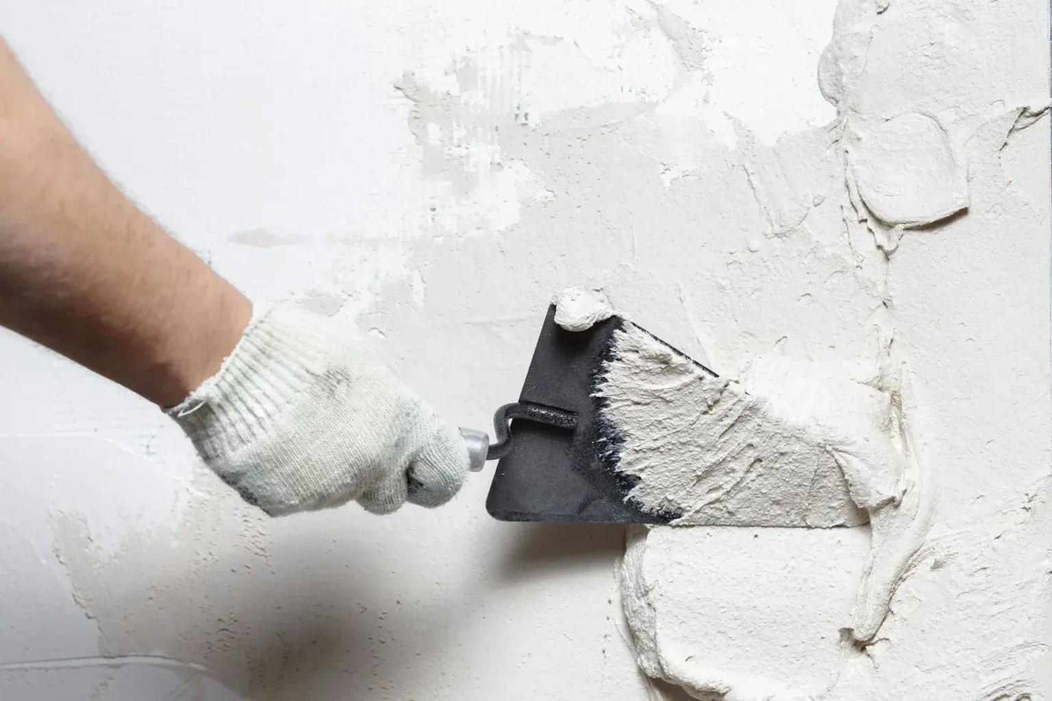 A man is working on a wall in a room.
