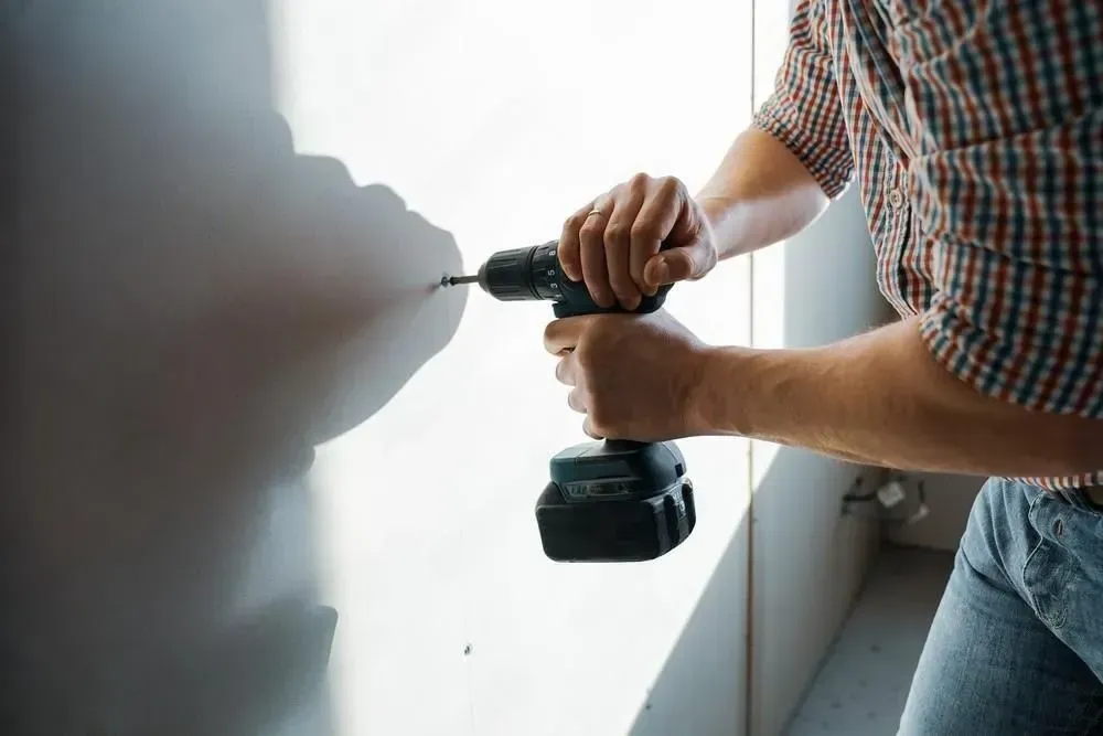 A man is working on a wall in a room.