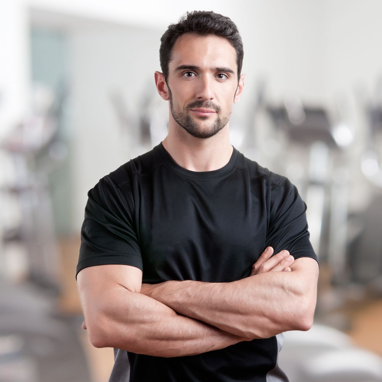 A man with his arms crossed in a gym