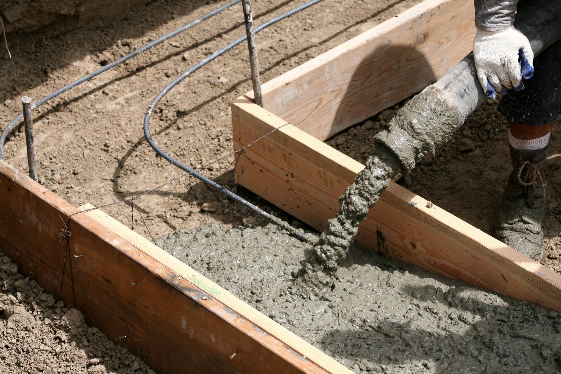 Concrete pump pours cement into the wooden footing form of a construction. Concrete pump pours cement into the wooden footing form of a construction.