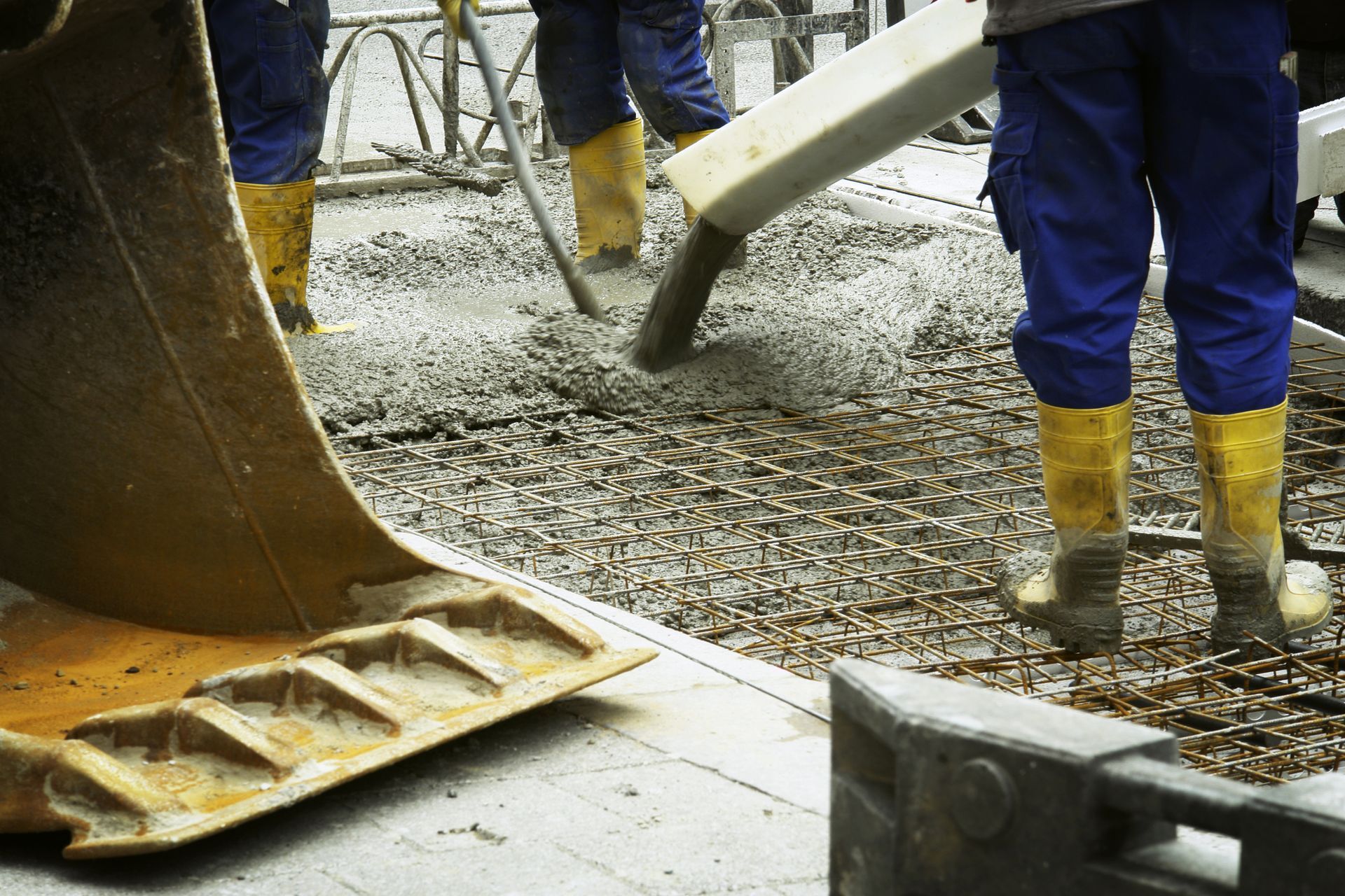 Worker pouring concrete on a commercial site with an engineer supervising.