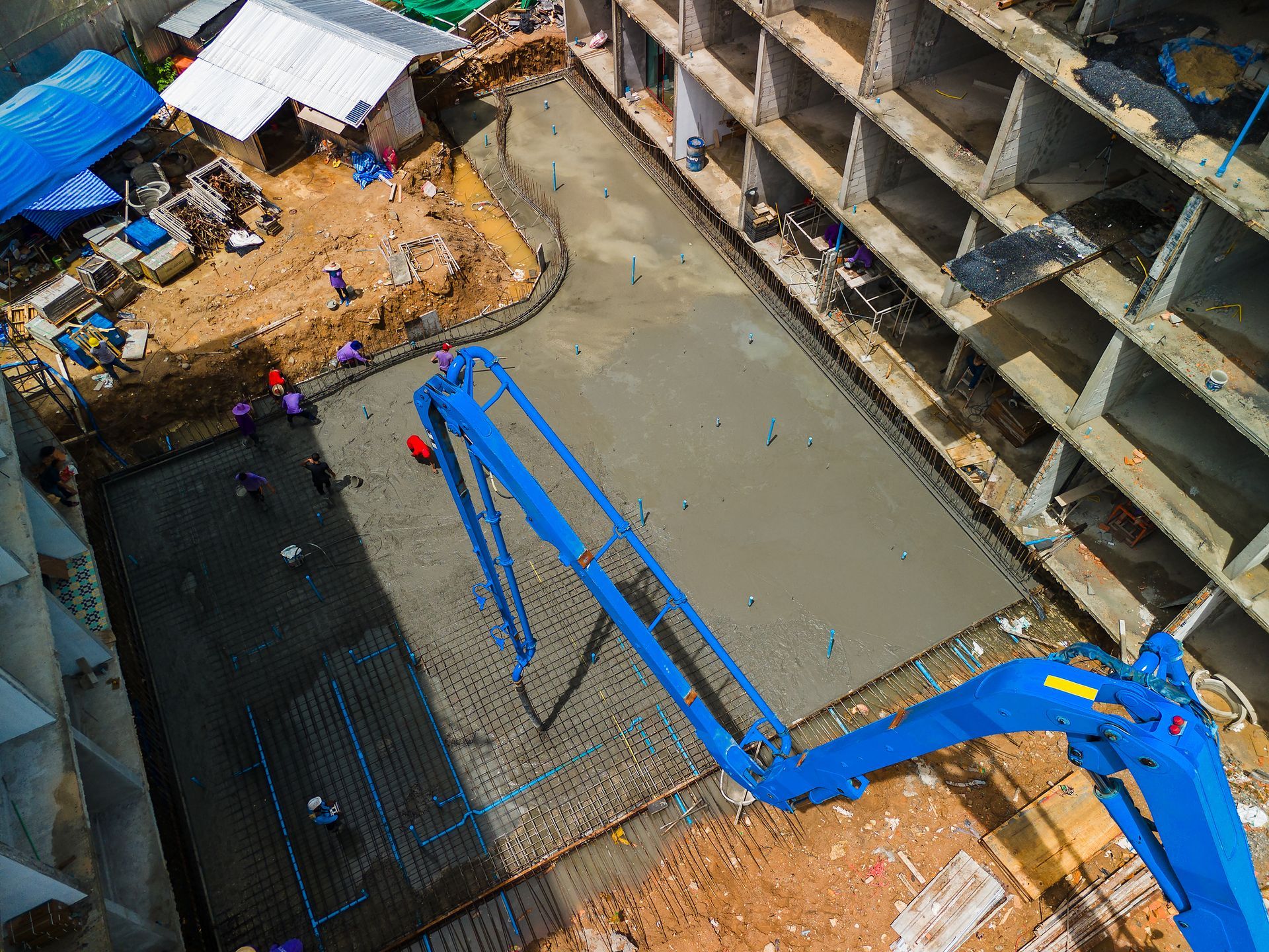 Commercial concrete pumping services at a large construction site with workers and trucks.