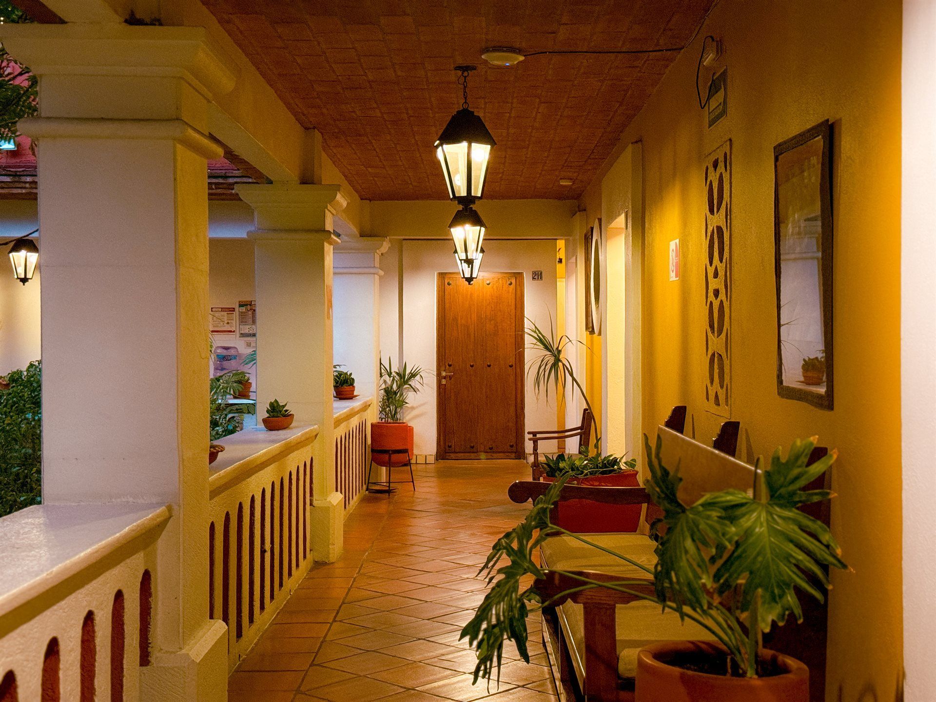 Un largo pasillo con plantas en macetas y faroles colgando del techo.HOTEL PARADOR DEL DOMINICO