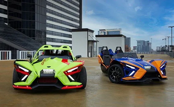 Two slingshot motorcycles are parked next to each other in a parking lot.