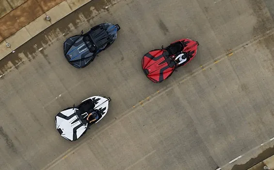 An aerial view of three slingshot cars driving down a road.