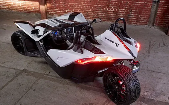 A white and black motorcycle is parked in front of a brick wall.