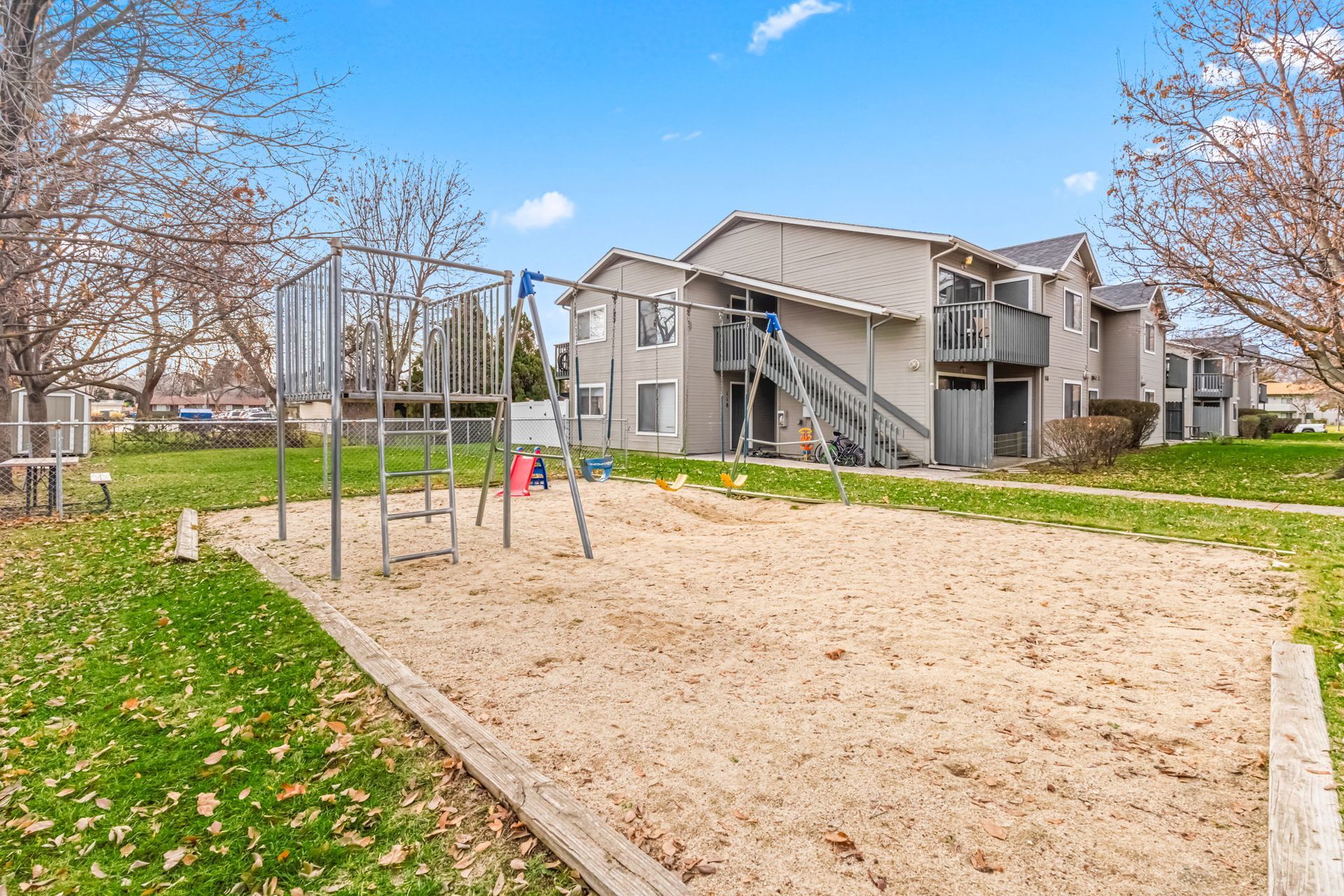 Playground with sand pit and apartment building in the background.