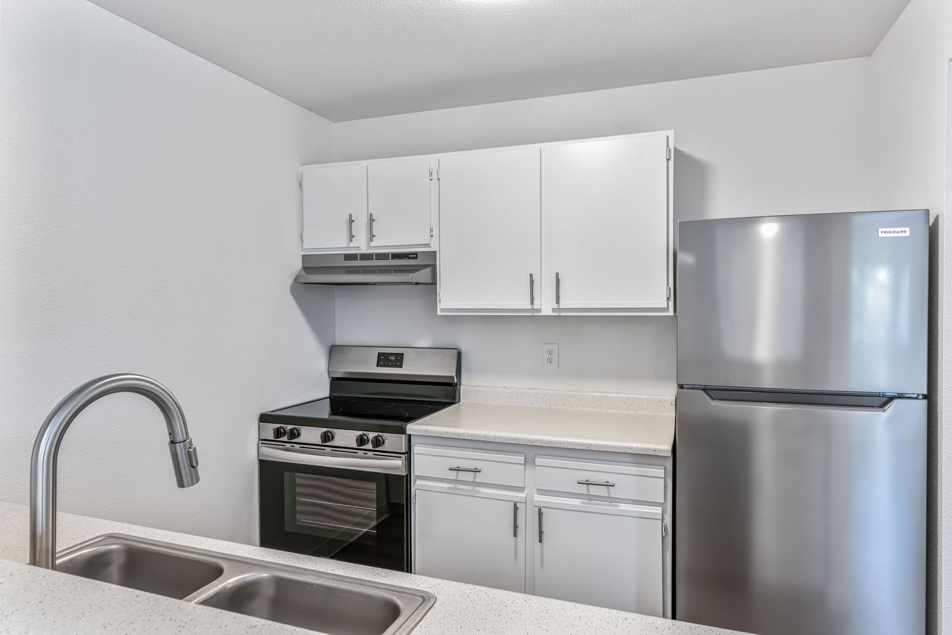 Kitchen with stainless steel refrigerator, white cabinets, and gas stove.