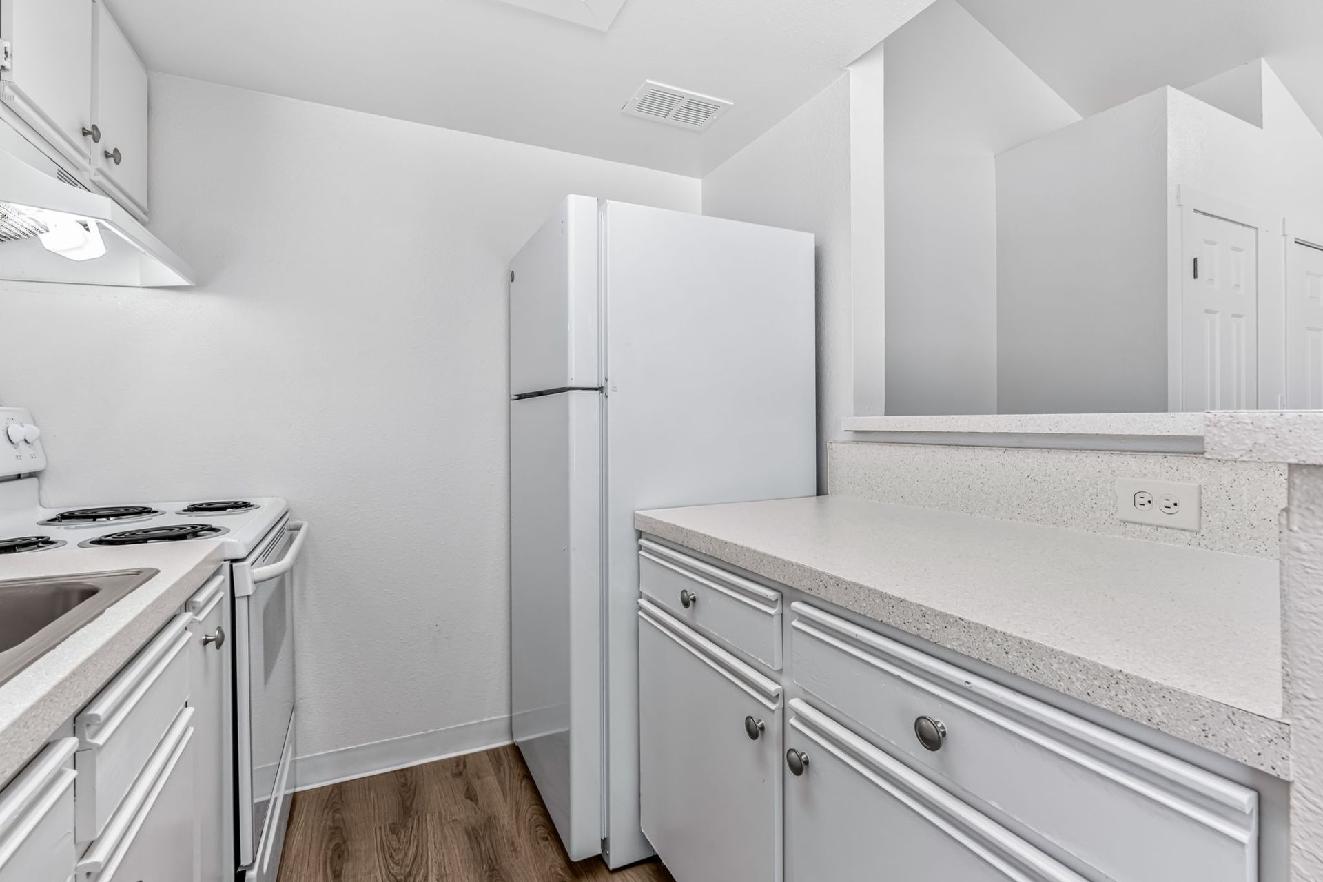 White kitchen with stove, refrigerator, cabinets, and countertop.