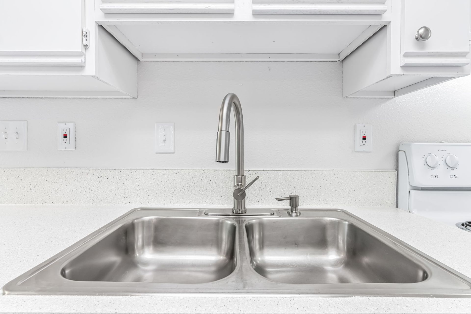 Stainless steel double sink with faucet in a white kitchen.