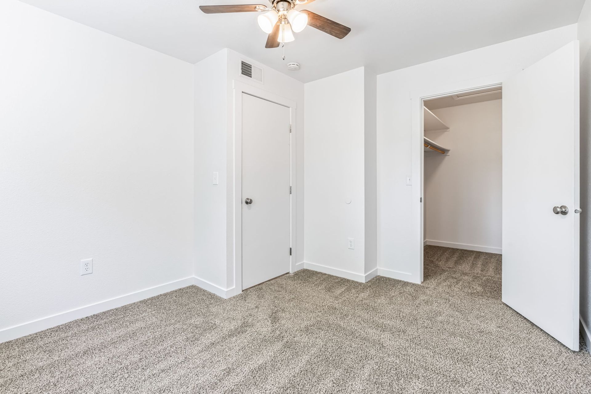 Empty bedroom with carpet, closet, and a closed door.