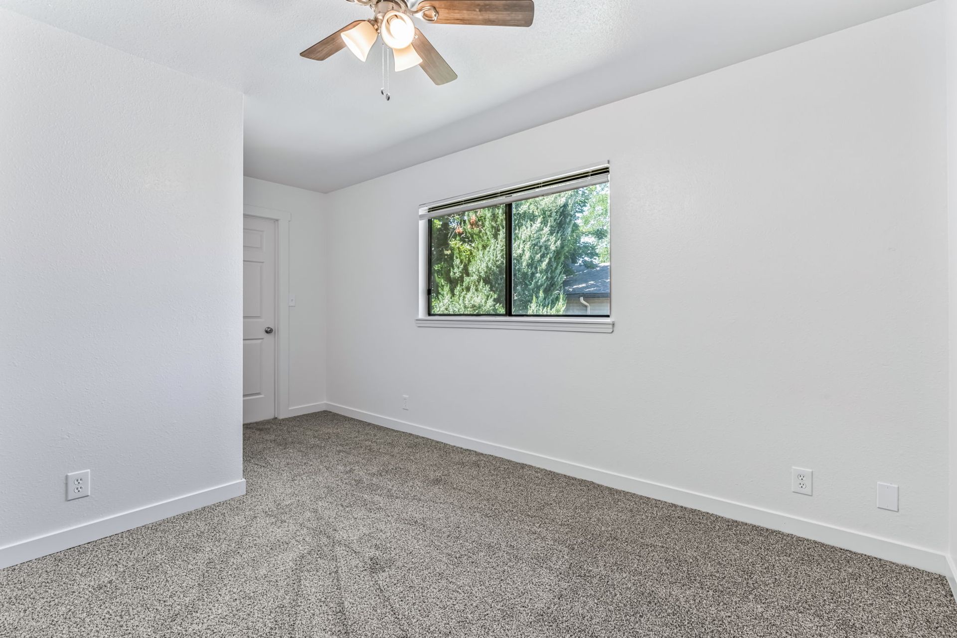 Empty room with beige carpet, white walls, a window, and a ceiling fan.