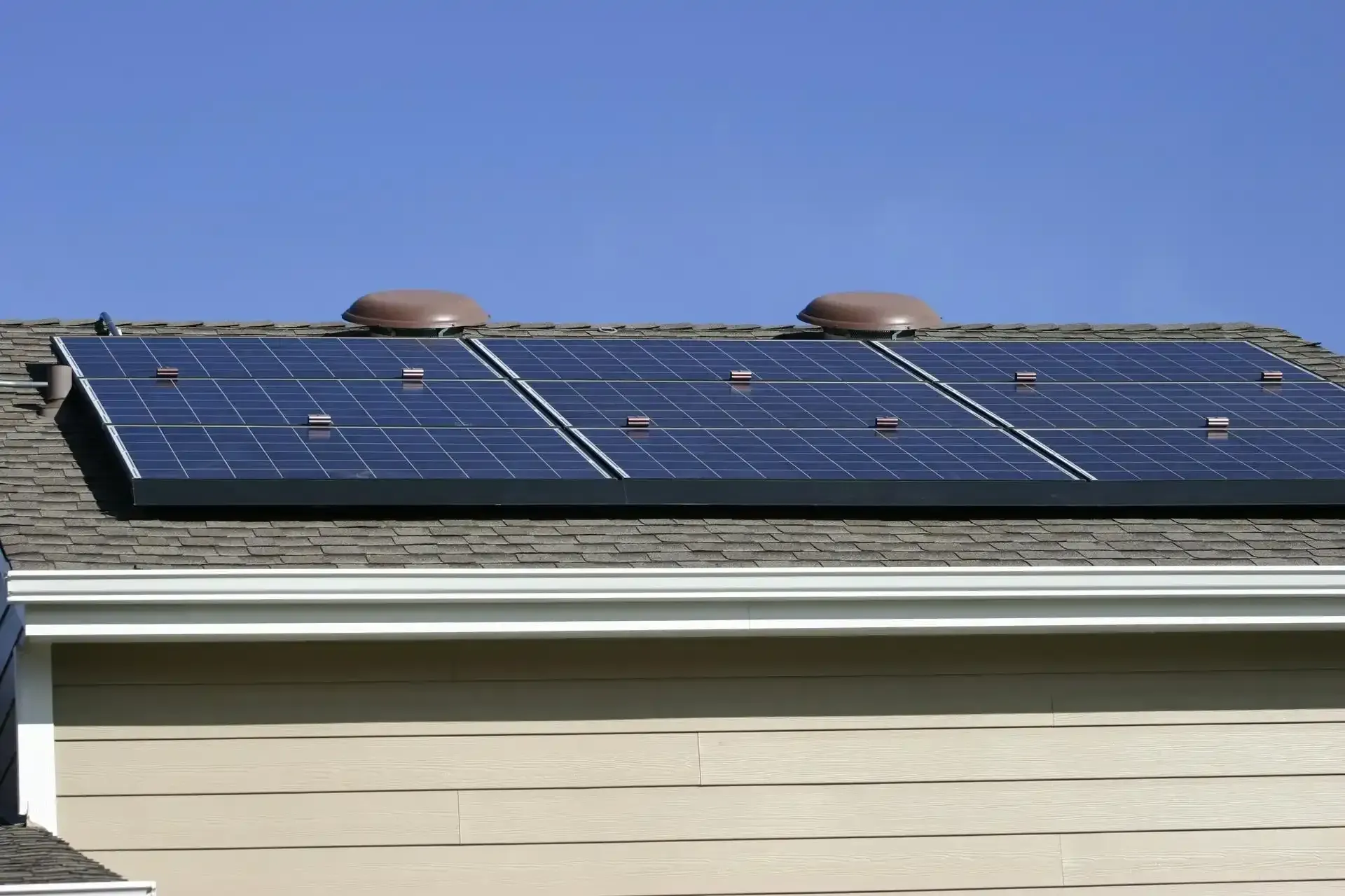 Solar Panels on a Roof with Two Brown Vents Solar Panels on a Roof with Two Brown Vents