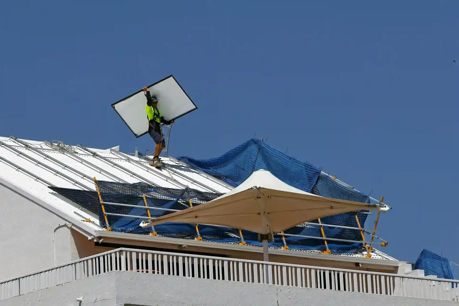 Worker on a Rooftop Holding a Large white Reflector Worker on a Rooftop Holding a Large white Reflector