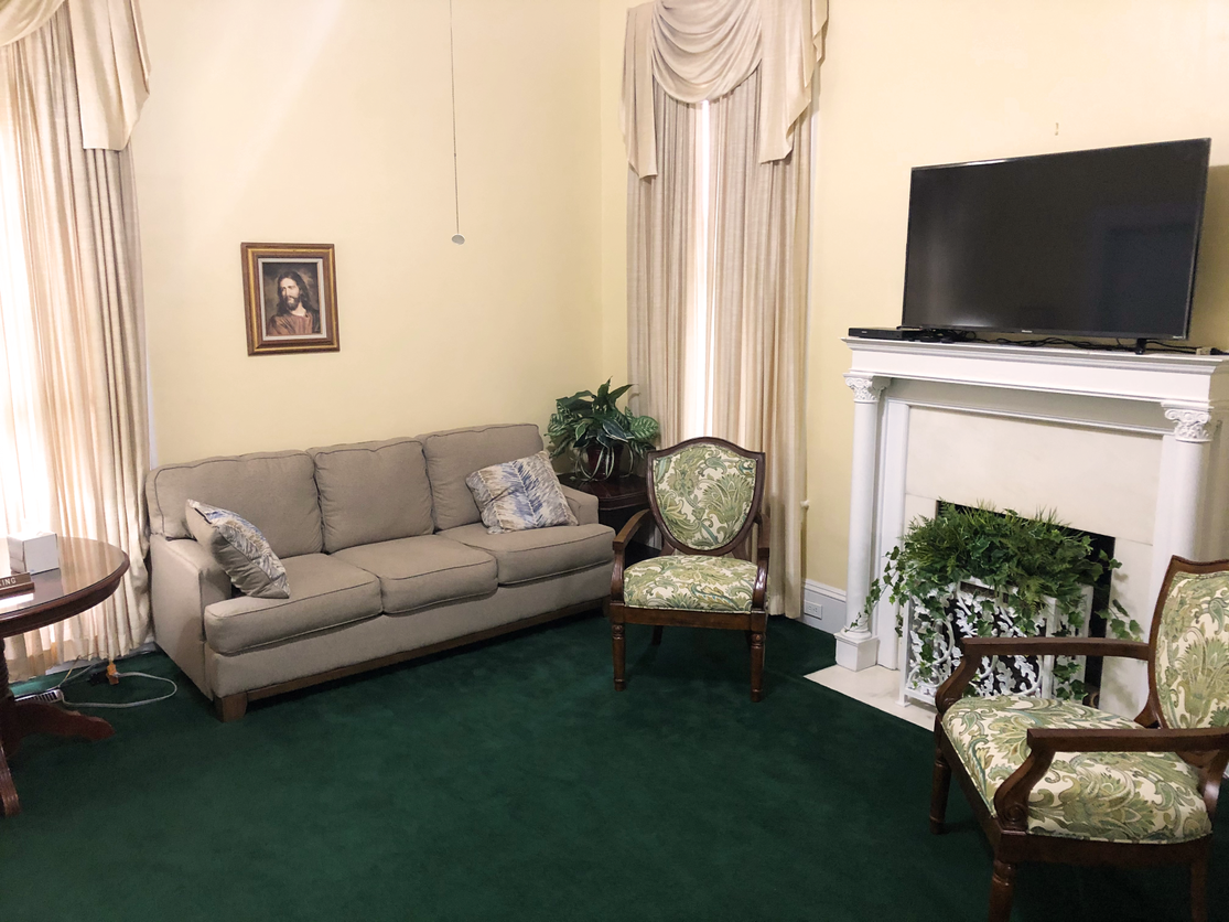 A living room with a couch , chairs , television and fireplace.