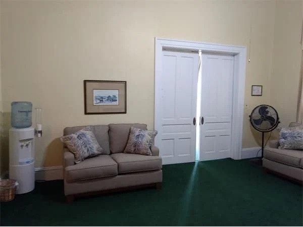 A living room with a couch a chair and a fan