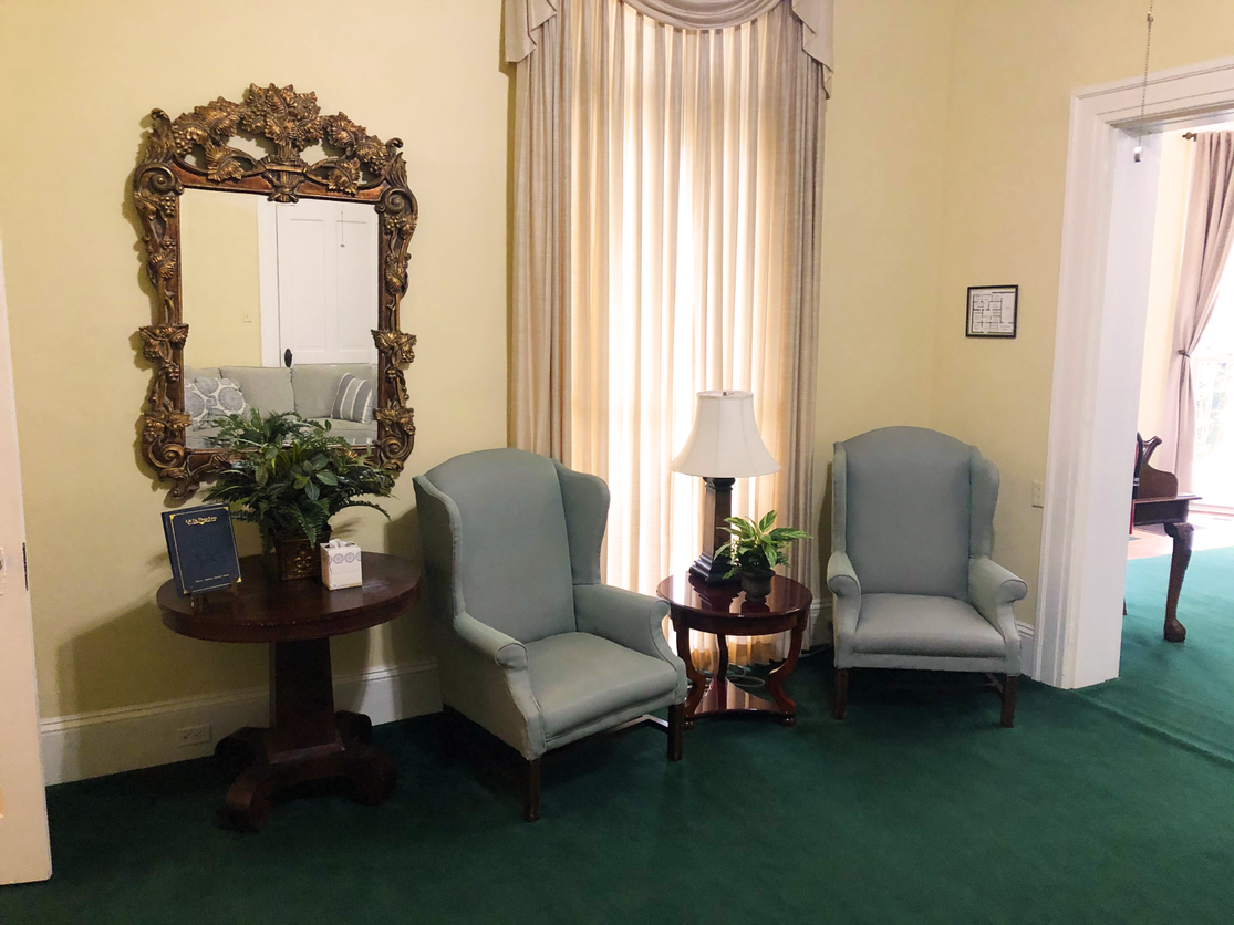 A living room with two chairs a table and a mirror