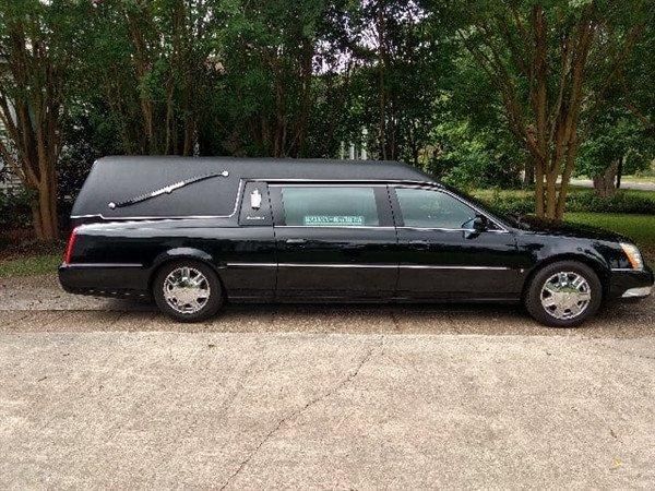 A black funeral car is parked on the side of the road.