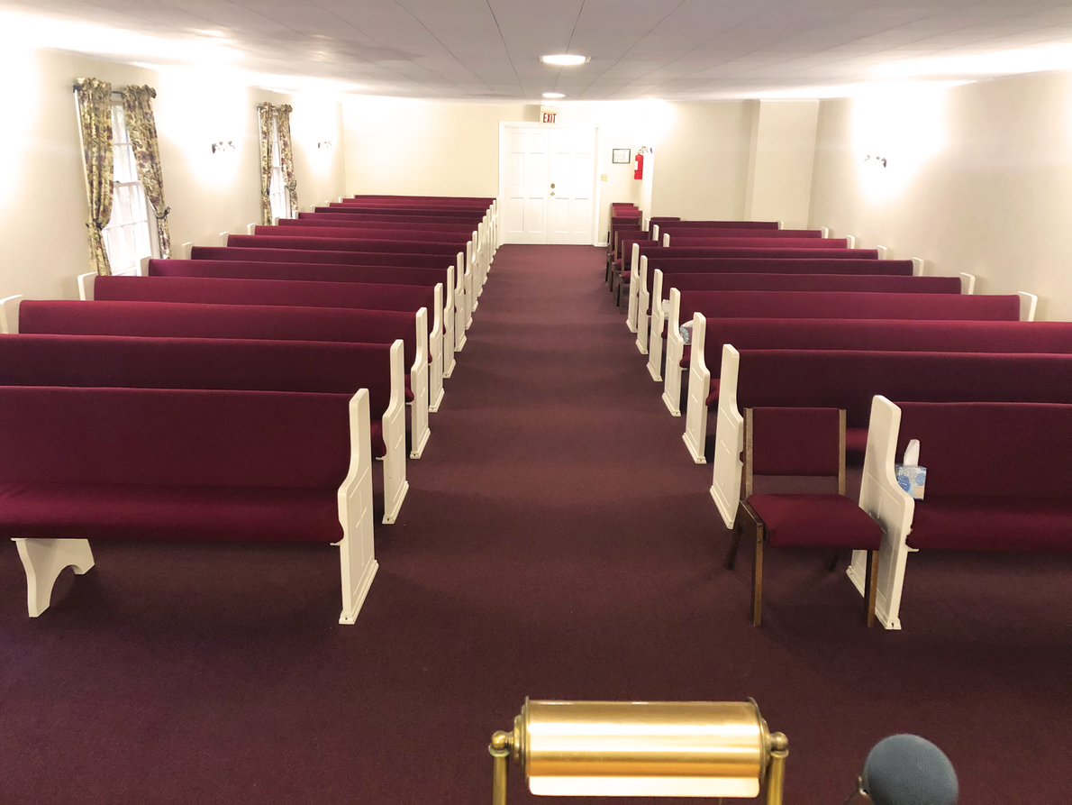 A church with rows of red benches and chairs