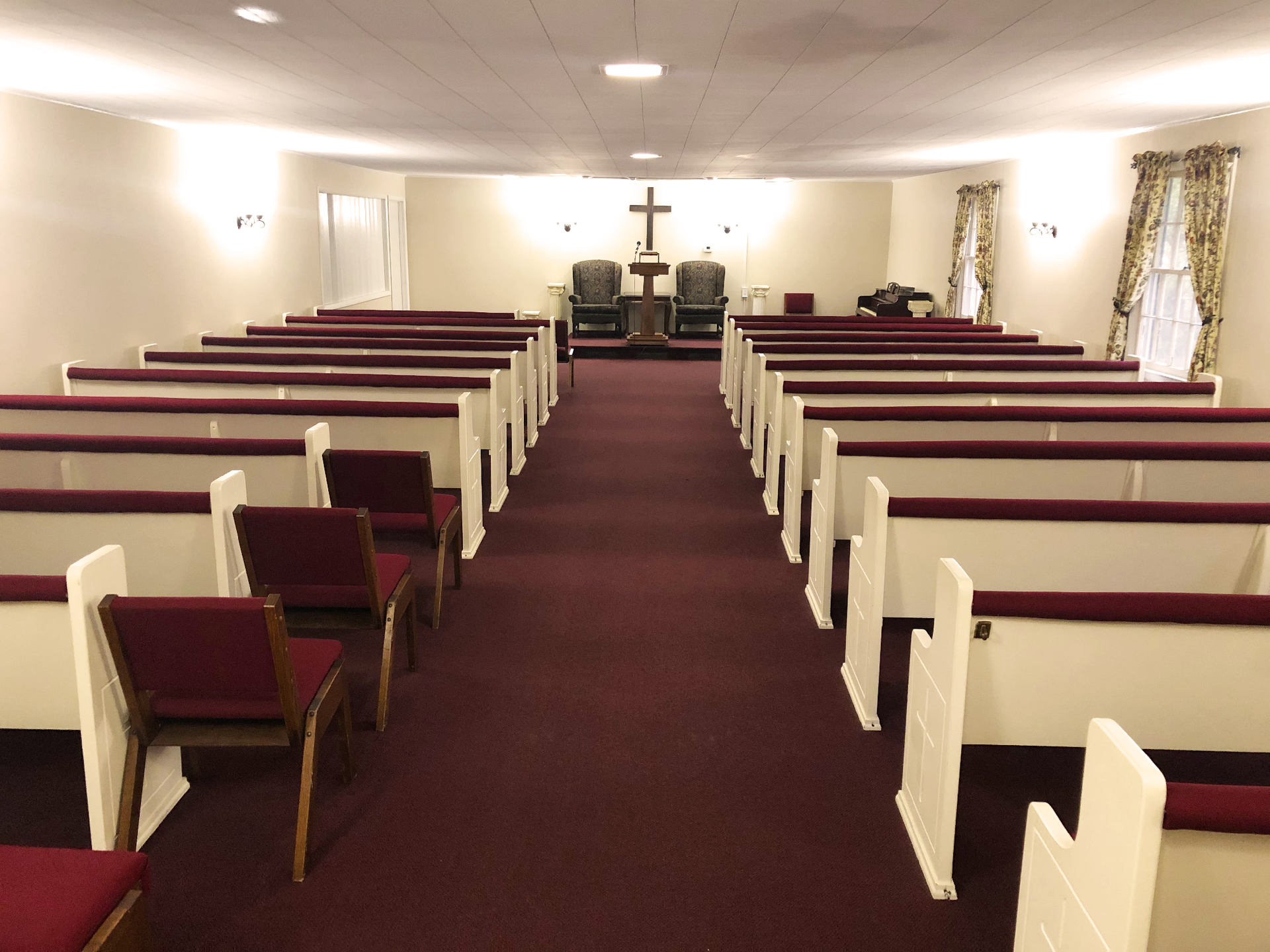 An empty church with red chairs and a cross on the ceiling