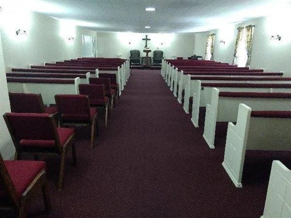 An empty church with red chairs and a cross in the middle